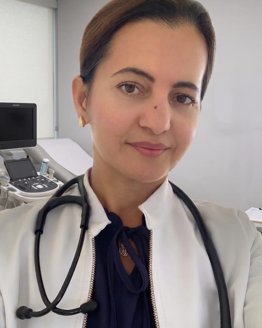 La Dra. Ydelise Rodríguez Pichardo, cardióloga, con bata blanca y fonendoscopio en su consulta, junto al ecógrafo